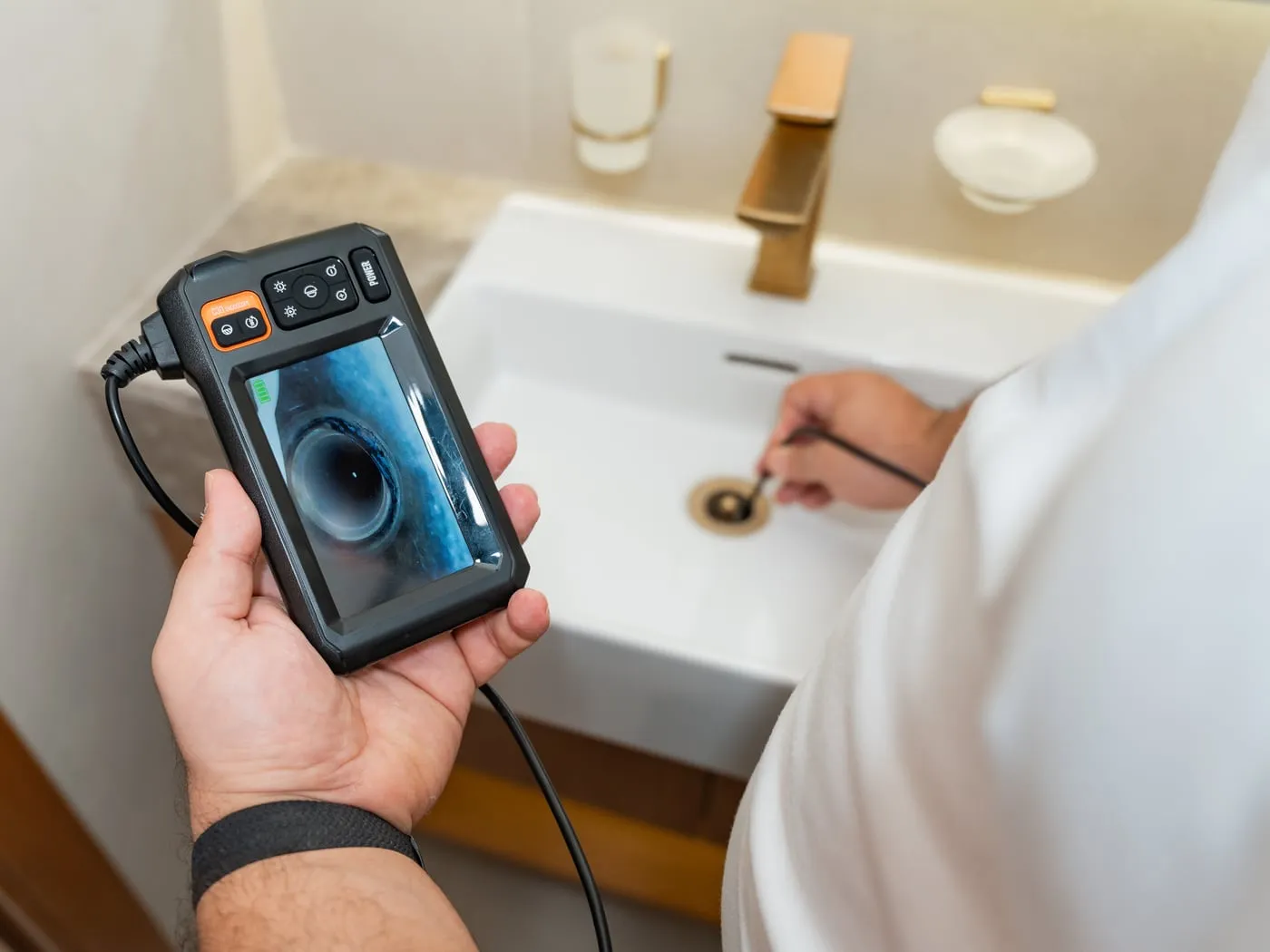 An engineer inspecting a basin drain with a borescope camera